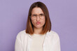 Portrait of Caucasian funny woman wearing white clothing and glasses, looking at camera with funny face and pout lips, posing isolated over purple background.