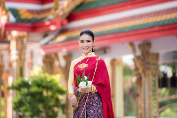 Portrait of young Asian women in traditional Thai costumes worshiping Buddha images with flower garlands. Preserving the good culture of Thai people during Songkran Festival, Thai New Year, April Fami