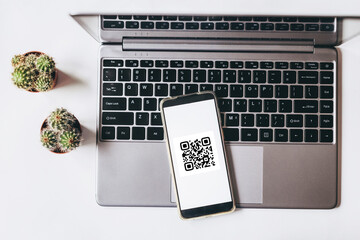 QR code scanning payment and online shopping concept. Mobile phone on the laptop.
