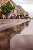 Fototapeta Miasto - Deszczowa pogoda i odbijający się w kałuży ludzie