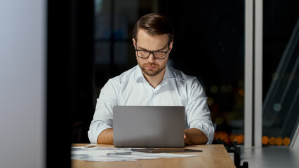 Poster - Serious young man typing message on laptop keyboard in office