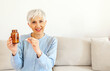 © Jelena Stanojkovic - Happy middle aged 60s Caucasian woman holding pill, taking dietary supplements. Portrait of smiling mature attractive woman taking care of health in menopause, copy space.