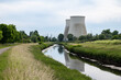 Vilvoorde, Flemish Brabant, Belgium - Cyclist on a bicycle trail at the banks of the river Senne with two powerplant chimneys in the background