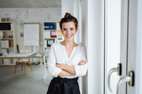 Fototapeta Na drzwi - Confident young businesswoman looks at camera laughing