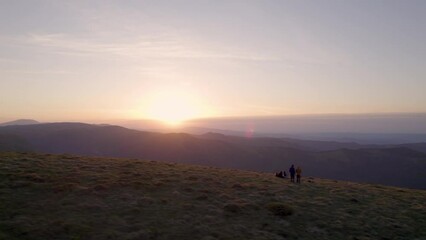 Wall Mural - Flying over the silhouettes of hikers watching the sunset at the top of the mountain while taking a rest