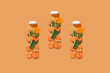 Bottle imitation of fresh smoothie from carrot, spinach, ginger and turmeric on orange background. Concept healthy vitamin eating, raw, snack to go, breakfast. Flatlay, pattern.