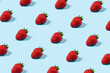 © Santijago - Sunlight summer pattern made with strawberries fruit on bright blue background. Minimal trendy food composition.