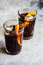 Close-Up Of Two Cola Drinks With Ice Cubes And A Slice Of Orange