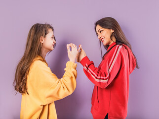 Wall Mural - Happy smiling beautiful playful mother and cute daughter have the peace and love in fashion trendy hoodie together on purple studio background with empty copy space. Happy