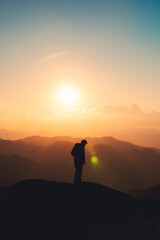 Hiker man standing on top of mountain enjoying the beautiful sunset in national park