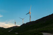Turbinas eólicas na paisagem montanhosa ao pôr do sol com uma estrada sobre a montanha
