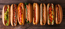 Many Tasty Hot Dogs On Wooden Background, Top View