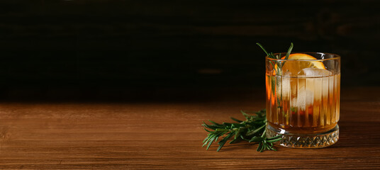 Glass of tasty Old Fashioned cocktail on table against dark background with space for text