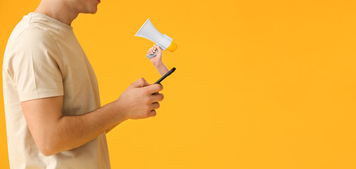 Wall Mural - young man with mobile phone and hand holding megaphone against yellow background