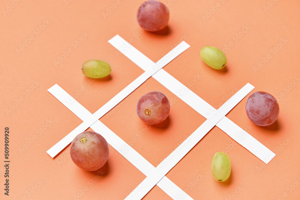 Game of Tic-tac-toe with fresh grapes on color background