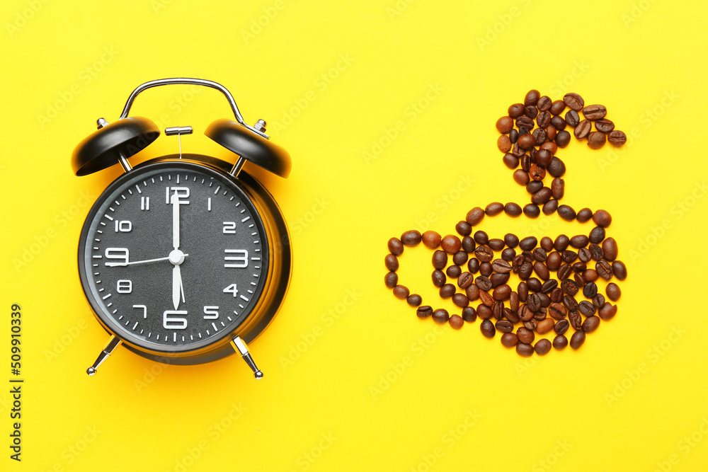 Cup made of coffee beans and alarm clock on yellow background