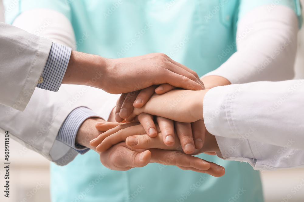 Group of doctors putting hands together in clinic, closeup
