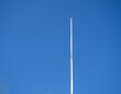 Empty white flagpole against the blue sky. Lowered flag.