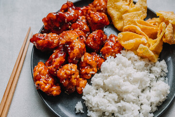 Wall Mural - General Tsos Chicken with white rice and crab rangoon on a dark dish