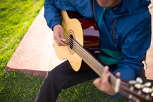 Detalle De Joven Cantando Y Tocando Guitarra En Un Parque Al Atardecer. Concepto De Personas Y Música.