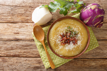 Wall Mural - Creamy pureed kohlrabi soup with bacon and parmesan close-up in a bowl on the table. Horizontal top view from above