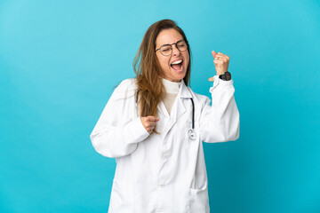 Wall Mural - Middle age Brazilian doctor woman isolated on blue background celebrating a victory