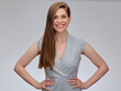 © Yuriy Shevtsov - Smiling woman with long hair in gray business dress standing with hands on hip, isolated on gray background.
