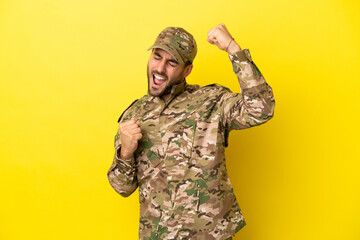 Wall Mural - Military man isolated on yellow background celebrating a victory