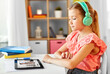 © Syda Productions - school, education and distance learning concept - little student girl in headphones with tablet computer having online class at home from top