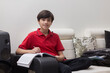 © IndiaPix - Portrait of cheerful young boy studying on sofa at home