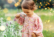 © Syda Productions - childhood, leisure and people concept - happy little baby girl with magnifier looking at flowers in summer garden