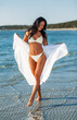 © Syda Productions - people, summer and swimwear concept - happy smiling young woman in bikini swimsuit with pareo on beach