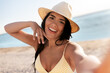 © Syda Productions - people, summer and swimwear concept - happy smiling young woman in bikini swimsuit and straw hat taking selfie on beach
