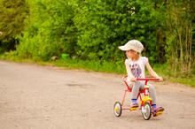 Little Girl With A Tricycle In The Park