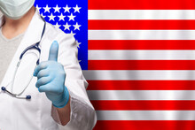 American Doctor's Hand Showing Thumb Up Positive Gesture On Flag Of USA Background.