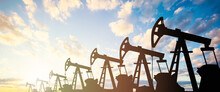 Oil Pump Jack. Oil Industry Equipment Silhouette Against Blue Sky Clouds Background