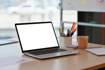 Poster - The close up of blank screen laptop computer on wooden desk with stationery and a cup of coffee over modern office decoration. Business and Technology concepts.