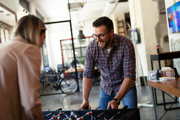 Colleagues having fun at work. Businessman and businesswoman playing table soccer.