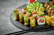 Sushi roll set with avocado, tuna, eel on black slate on dark background
