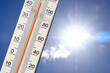 Thermomètre avec une double graduation degré centigrade et degré fahrenheit sur fond de ciel ensoleillé