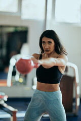 Wall Mural - A strong, muscular female weightlifter is doing squats with a kettlebell in a gym.