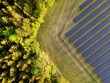 canvas print picture - Photovoltaikanlage - Solarpark - Freiflächenanlage mit grünem Wald und Wiese im Hintergrund. Luftbildaufnahme mit Drohne.