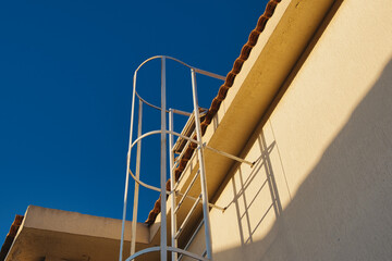 External metal staircase to the roof of the house. Fire escape access to the tiled roof.