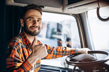 Man trucker driving in a cabin of his truck