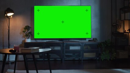Poster - Cozy Living Room with Stylish Furniture and Design, Green Chroma Key TV in the Middle of the Room. Evening View of the TV with Horizontal Mock Up Display. Motion Camera Shot.