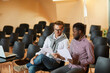 © Mediaphotos - Pensive young multi-ethnic business colleagues in casual outfits sitting on plastic chairs in meeting room and reading report while preparing for presentation