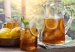 Glass and pitcher of ice tea with rural summer background
