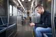 Side view of passenger while using phone. Man commuting by train of public transportation. .