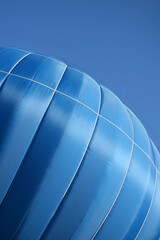 The blue hot air balloon is rising up into the sky. Blu-coloured hot air baloon flying in the blue sky. Copy Space