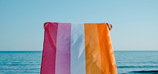 Poster - holding a lesbian pride flag facing the sea